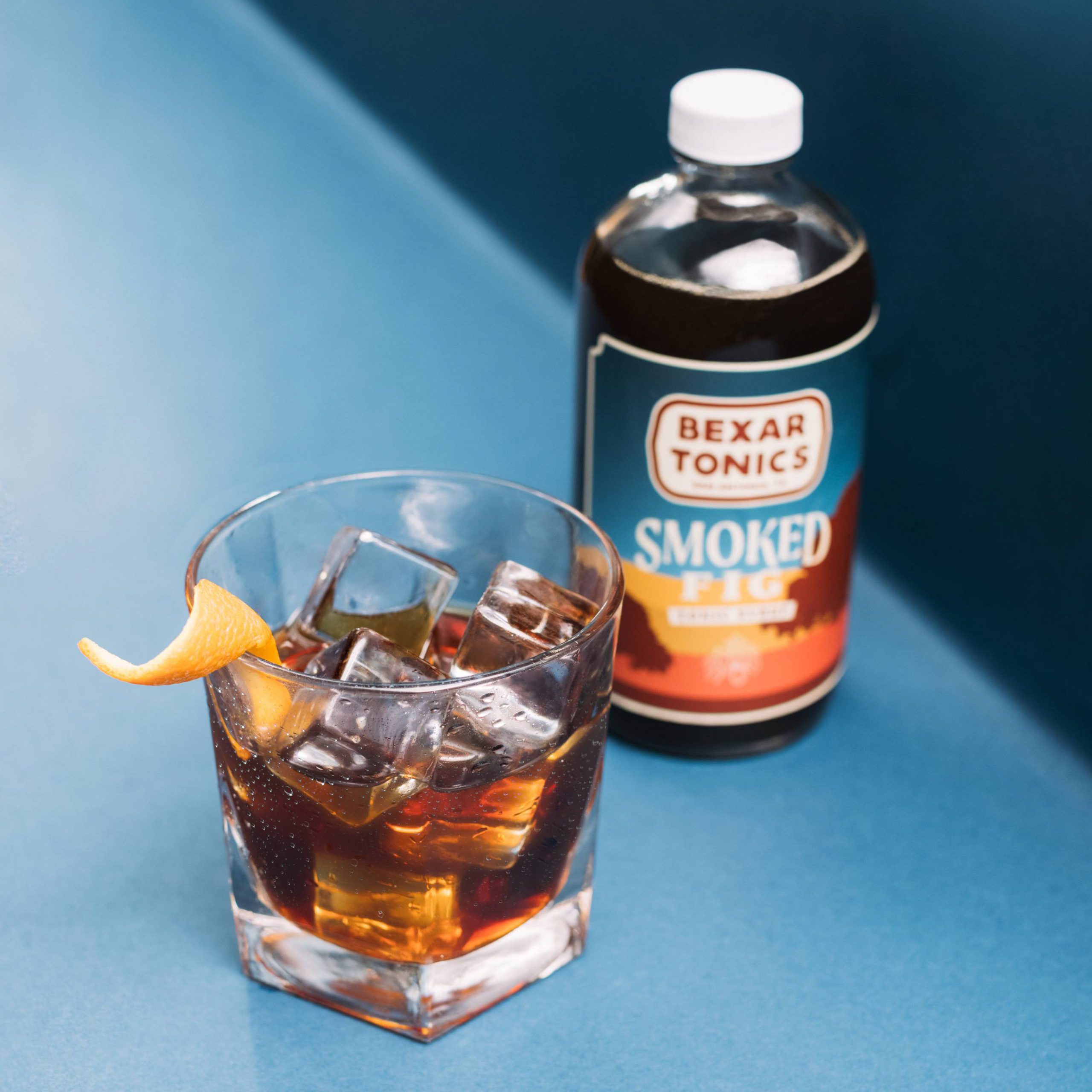 bottle of smoked fig tonic syrup with  cocktail
