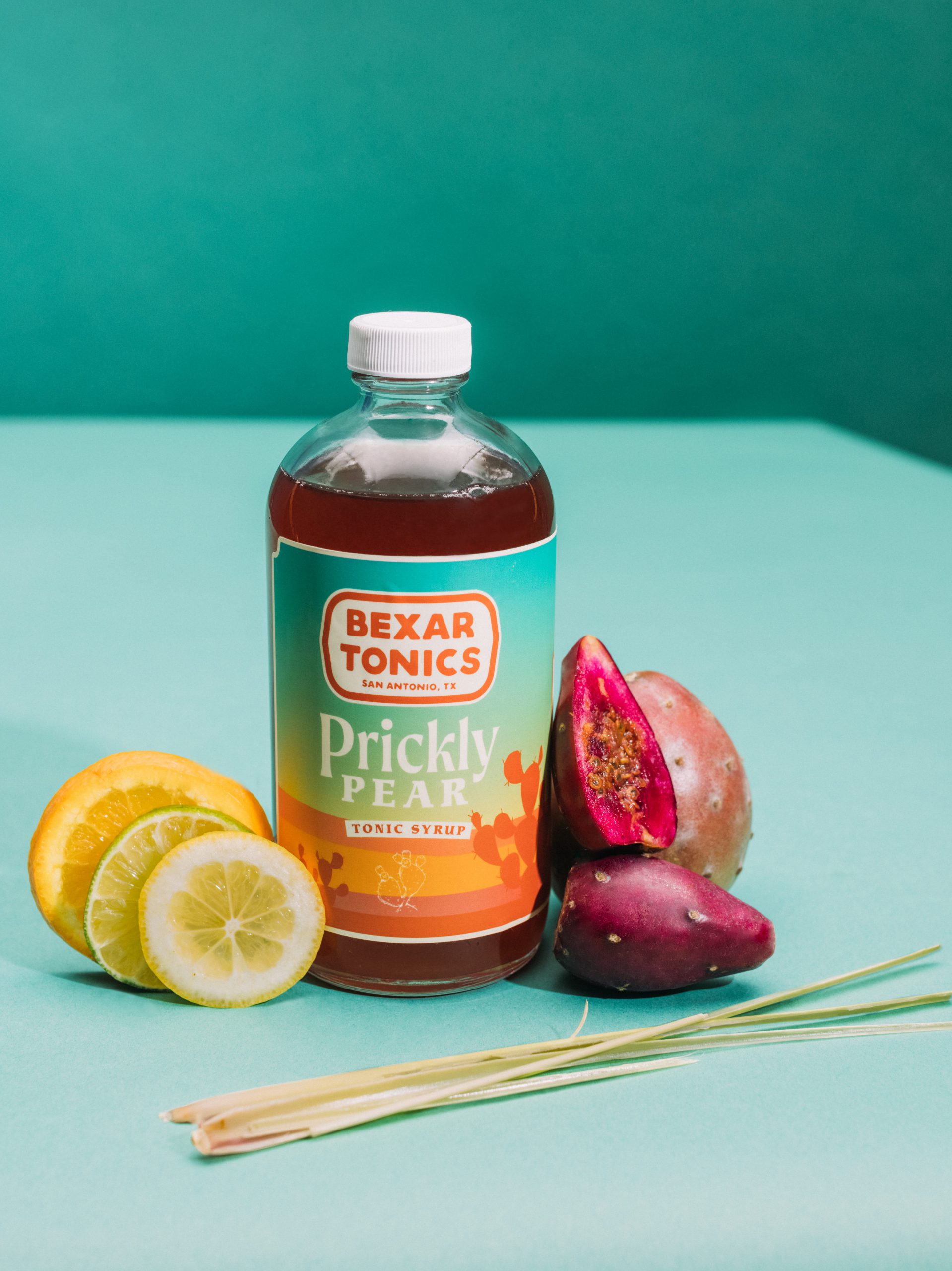 bottle of prickly pear tonic displayed with fresh local ingredients
